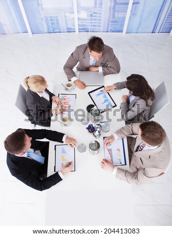 High angle view of young business people discussing on graphs at conference table