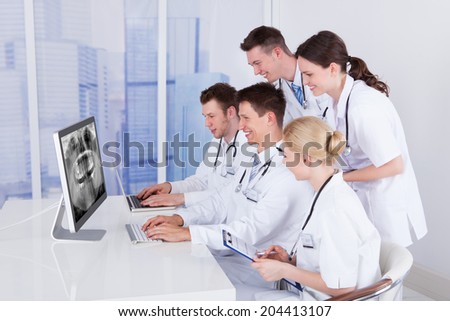Team of dentists examining jaw Xray on computer in hospital Team of dentists examining jaw Xray on computer in hospital