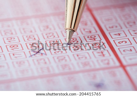 Closeup of pen marking numbers on lottery ticket