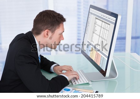 Side view of concentrated businessman working on computer at desk in office