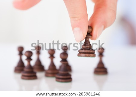 Cropped image of woman\'s hand holding chess pawn on table