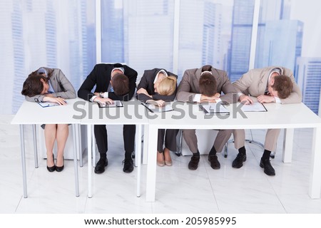 Group of tired corporate personnel officers sleeping at table in office
