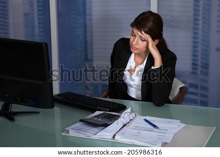 Stressed young businesswoman working at computer desk in office