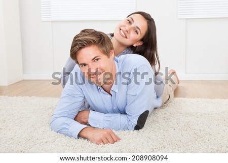 Portrait of happy loving couple lying on rug in living room
