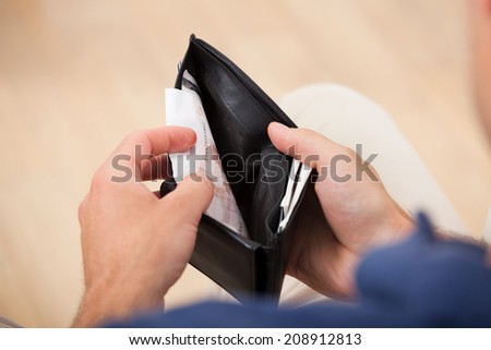 Cropped image of broke man holding wallet at home