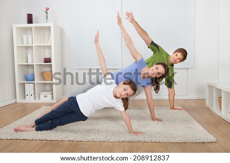 Full length portrait of fit family doing side plank yoga on rug at home