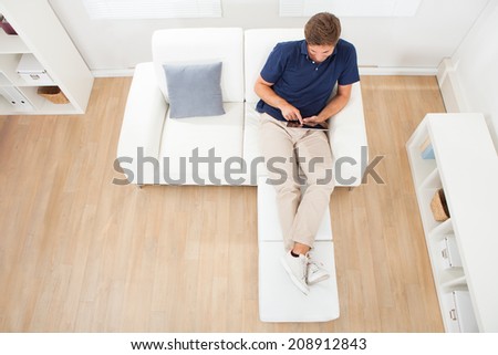 High angle view of relaxed man using digital tablet in living room at home