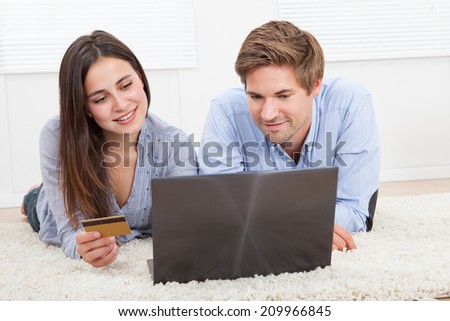 Happy couple using laptop and credit card to shop online at home