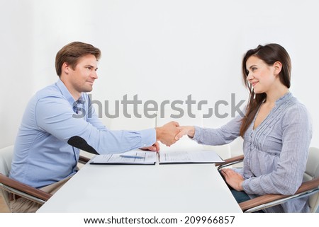 Smiling female candidate shaking hands with businessman in office