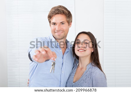 Portrait of happy couple holding keys in new house