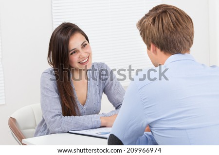 Happy female candidate looking at businessman during interview in office