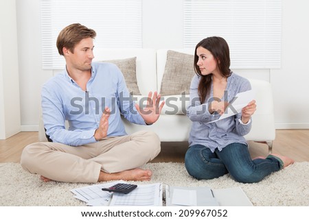 Serious young woman blaming man for excessive expenses at home