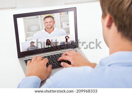 Rear view of businessman video conferencing on computer at desk in office