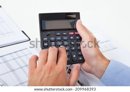 Cropped image of businessman calculating tax at desk in office