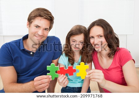 Portrait of happy family joining puzzle pieces at home