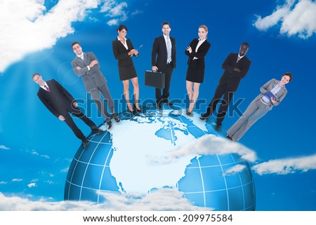 Confident multiethnic business people standing on globe against blue sky.