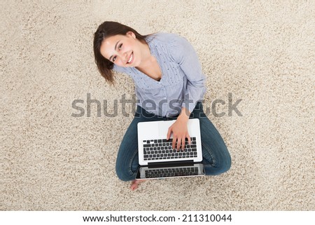High angle portrait of young woman using laptop on rug at home