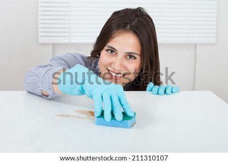 Close-up of woman\'s hand cleaning dirt on table with sponge at home