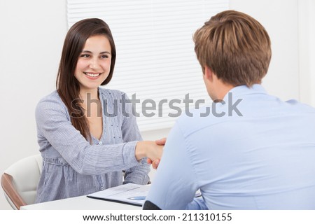 Happy female candidate shaking hand with businessman in office