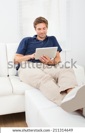 Relaxed man using digital tablet in living room at home