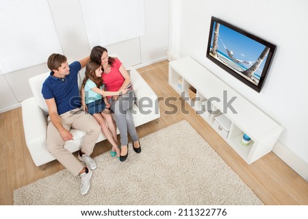 High angle view of family watching TV together while relaxing on sofa at home