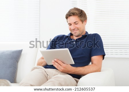 Relaxed man using digital tablet in living room at home