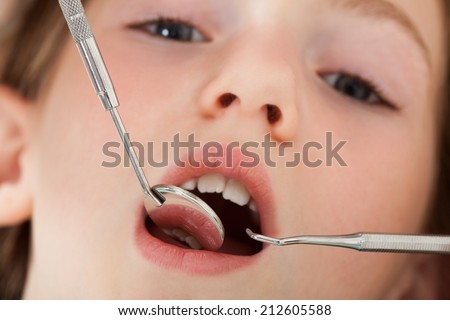 Close-up portrait of girl with mouth open going through dental examination in clinic