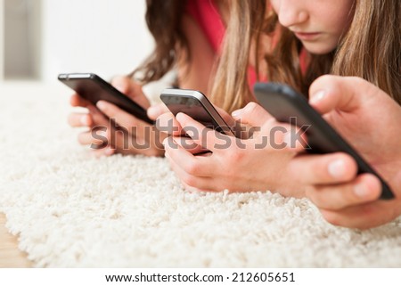 Cropped image of family using smart phones on rug at home