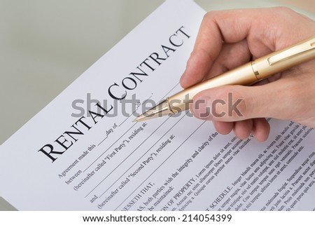 Cropped image of hand filling rental contract form on desk