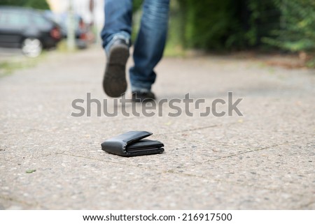 Low section of man walking against fallen wallet on street