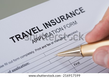 Cropped image of hand filling travel insurance form on desk