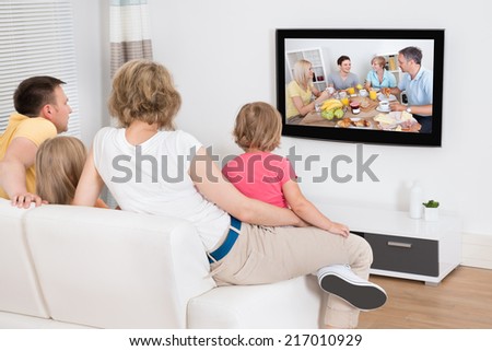 Young Family Watching TV Together At Home