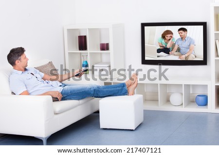 Mature Man Sitting On Couch Watching Television