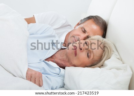 Portrait Of Happy Senior Couple Sleeping Together In Bed