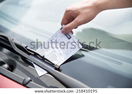 Close-up of officer\'s hand putting parking ticket on car windshield