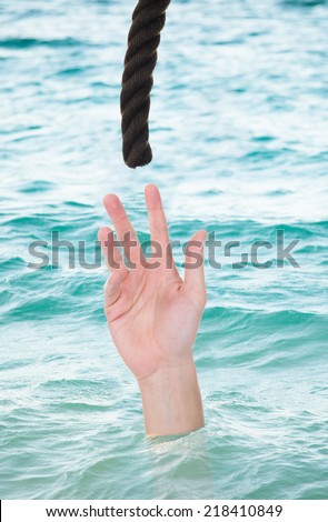 Man reaching for rope while drowning in water