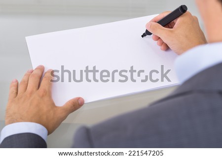 Businessman writing on empty paper sheet. Over the shoulder view
