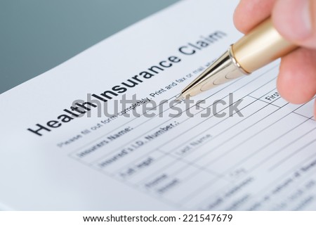 Hand filling health insurance claim form. Closeup shot