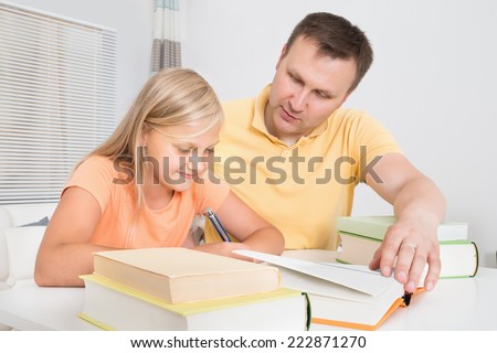 Father Helping Daughter With Homework At Home