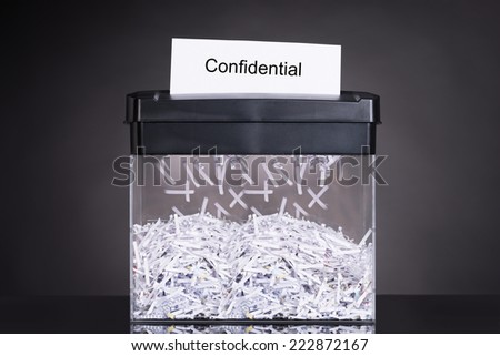 Shredded destroying confidential document over black background