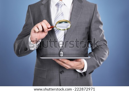 Auditor holding magnifying glass and tablet. Over blue background