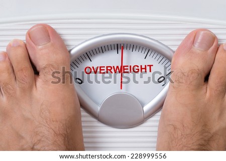 Closeup of man\'s feet on weight scale indicating Overweight