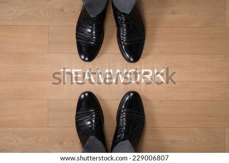 Directly above shot of businessmen standing with Teamwork written on hardwood floor