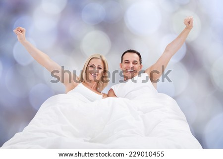 Portrait of successful couple with arms raised on bed