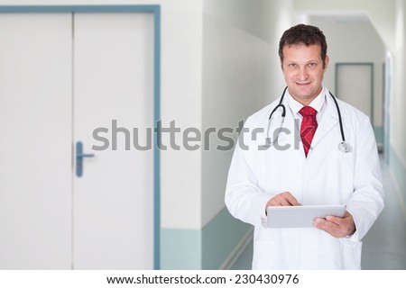 Portrait of confident doctor using digital tablet in hospital corridor