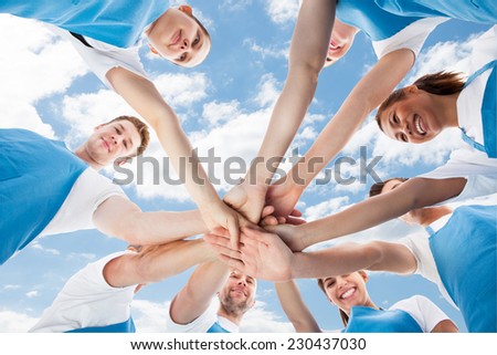 Directly below shot of diverse professional cleaners piling hands against sky