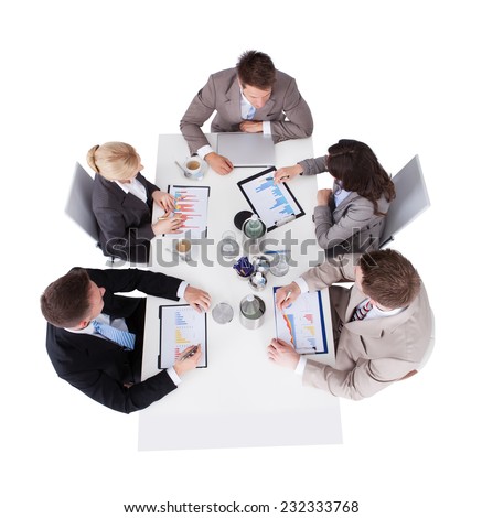 High angle view of business people discussing over financial graphs at conference table against white background
