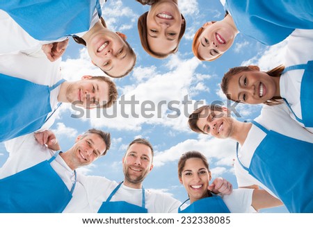 Directly below shot of diverse professional cleaners standing in huddle against sky