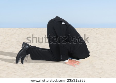Side view of businessman hiding his head in sand
