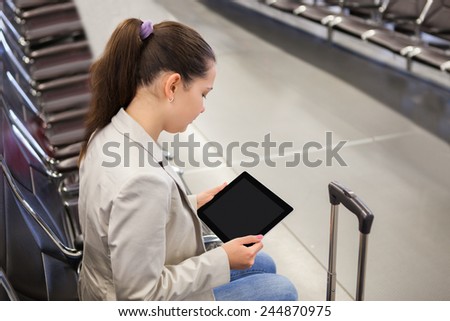 Young businesswoman using tablet computer while waiting for flight at airport lobby